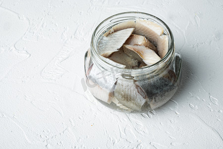 罐装野生鲱鱼片，在玻璃罐中，白色背景，带有复制空间和文本空间