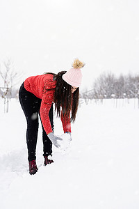 穿着红色毛衣的黑发年轻女子在公园里玩雪