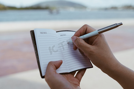 女人手写在白色的小笔记本上，记下不要忘记或做清单计划。