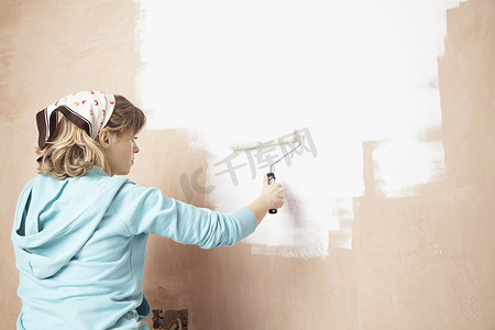 女人用油漆滚筒粉刷内墙