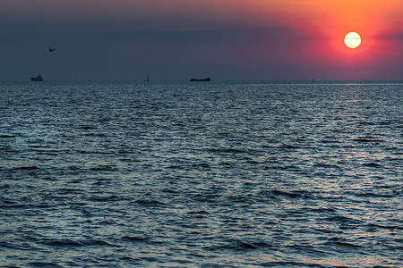 美丽的夕阳在平静的海面与蓝色和橙色的发光天空。