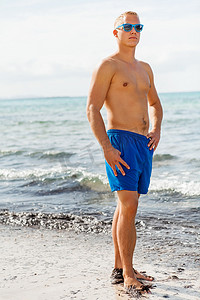 泳衣帅哥摄影照片_蓝色游泳短裤的人在海滩