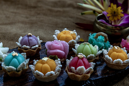 各种优雅美丽的泰式甜点 (Khanom Wan Thai) 五颜六色的变化在深色木头中供应，金色和不同花朵形状的叮咬，泰式甜点，吉祥甜点。
