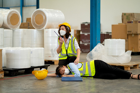 工厂女工使用对讲机寻求帮助，以支持和拯救在仓库工作区工作期间晕倒并躺在地板上的同事。
