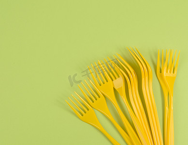 塑料叉子摄影照片_绿色背景中的一堆黄色塑料叉子，顶视图
