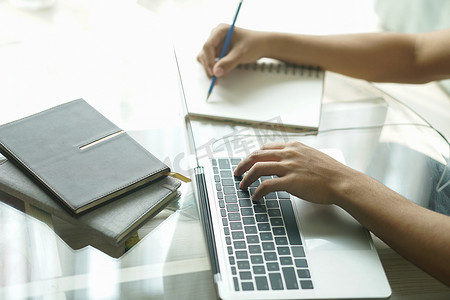 亚洲年轻学生男企业家在家里用电脑写笔记学习在线学习。