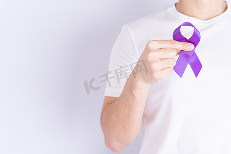 战天摄影照片_世界癌症日，手拿着灰色背景上的紫色丝带，带有文本复制空间。