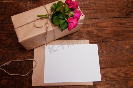 用工艺纸做的礼物，旁边是一束玫瑰花，放在一张木桌上