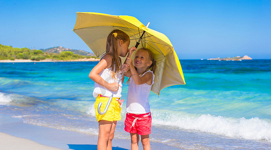 热带海滩度假时带黄色大伞的小女孩