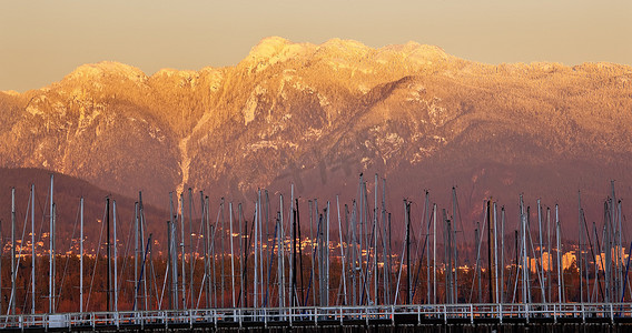 温哥华虽然帆船桅杆与金色的雪山背景