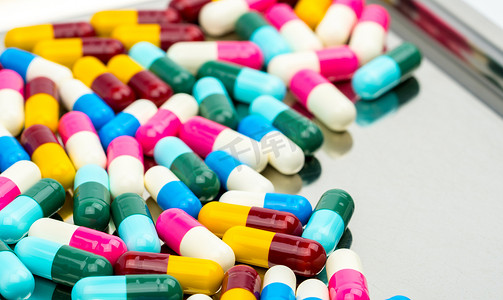 五颜六色的抗生素胶囊药片在不锈钢药盘上有阴影，抗菌药物耐药性概念。