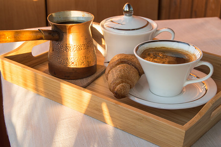 总结复盘摄影照片_木盘上的美味经典早餐 — 复古铜 cezve、一杯咖啡和羊角面包，黎明背景