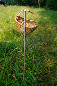 绿色杆子摄影照片_特写野餐篮挂在草地上的一根杆子上，外面有绿色自然背景