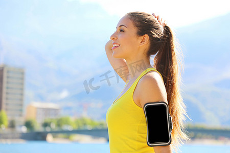 早上在城市湖上呼吸新鲜空气的智能手机臂带空白放松健身女性的侧面肖像。