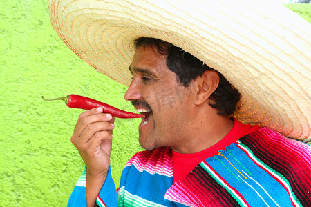 墨西哥人摄影照片_吃炽热辣椒的墨西哥人雨披阔边帽