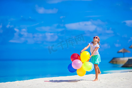 在热带海滩玩彩色气球的小女孩