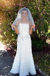 新娘礼服的秀丽新娘有花束和花边面纱的在自然。