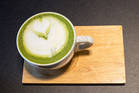 一杯拿铁艺术咖啡，放在木头上，绿茶牛奶