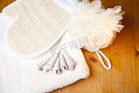 “豪华浴缸或淋浴套装，木质背景配有毛巾、手套和贝壳”