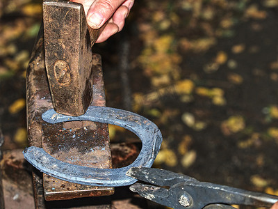 熟练的铁匠在铁砧上敲击一个炽热的马蹄铁。