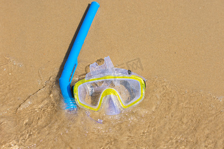 游泳面罩和呼吸管在水下呼吸，躺在水边的沙滩上