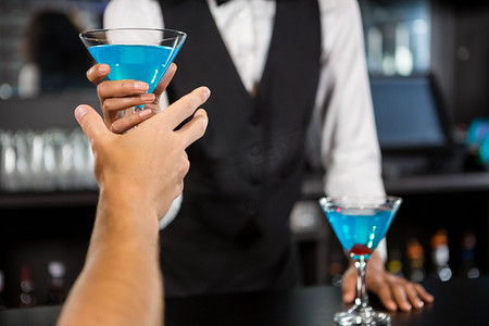 酒保在酒吧柜台供应蓝色鸡尾酒