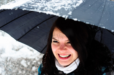 带伞摄影照片_暴风雪中带伞的年轻女子