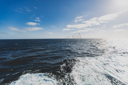 浩瀚船舶摄影照片_在明亮的阳光下穿越海洋时在船后挥手