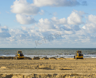在海滩上使用设备机器进行维护的推土机正在移动沙子