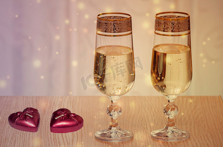 倾倒的酒杯摄影照片_两个装满香槟和蜡烛的酒杯。