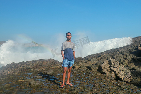 蓝色圆形海浪摄影照片_海浪拍打着圆形的岩石，溅起水花。