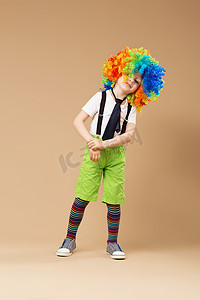 开心跳跃的小男孩摄影照片_小丑假发跳舞和玩得开心的小男孩