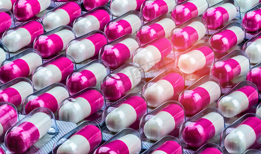 禁忌症摄影照片_在泡罩包装中特写粉色白色抗生素胶囊药丸。