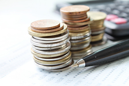 储蓄账簿或财务报表上的硬币堆、笔和计算器