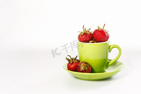 新鲜多汁的草莓在绿色杯子和碟子上隔离