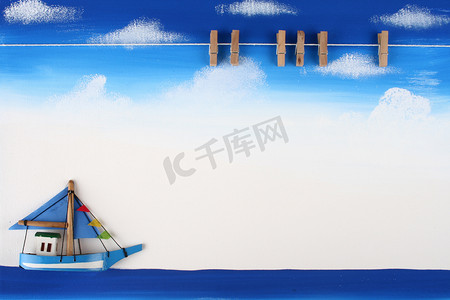 蓝天、海洋和小船上带有木制回形针的画板