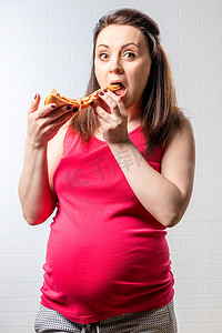 饥饿的孕妇在砖 whi 上放了一大片比萨饼