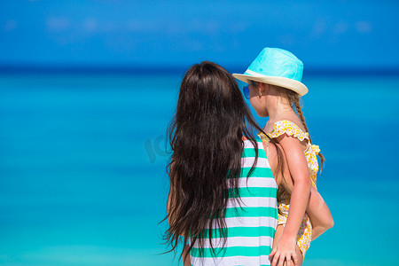 家庭度假摄影照片_海滩度假期间的小女孩和年轻妈妈