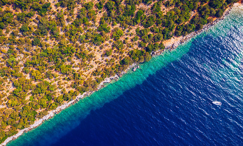 沿海地区有蓝色清澈的海水和陆地上的森林，无人机拍摄的鸟瞰图。