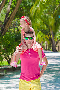 家庭度假摄影照片_热带海滩度假期间的小女孩和年轻父亲