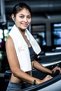 戴着耳机在跑步机上微笑的女人