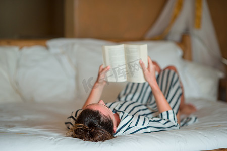 台灯看书摄影照片_美丽的女人在床上看书放松