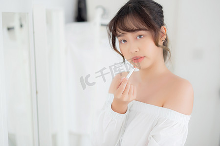 美丽的肖像年轻亚洲女人看着镜子应用 mak