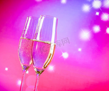 紫色气泡饮料摄影照片_蓝色和紫色浅色背景上带有金色气泡的香槟长笛