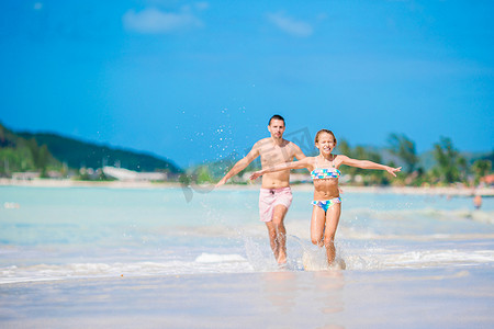 爸爸和孩子运动摄影照片_享受海滩暑假的父亲和孩子