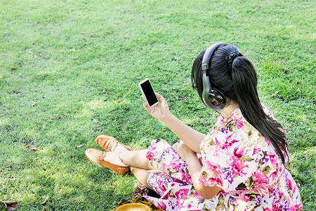年轻的亚洲女性回来或罕见地通过耳机听音乐
