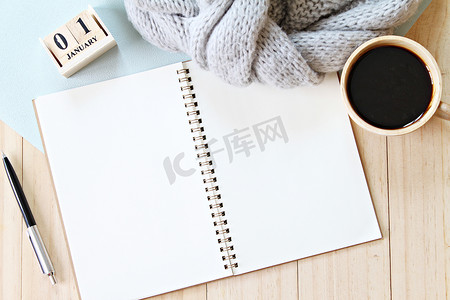 灰色针织围巾的平躺或顶视图、打开空白笔记本纸、咖啡杯和木制背景的新年立方体日历