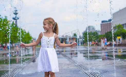 大热天，快乐的小女孩在户外喷泉里玩得开心