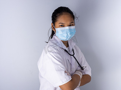 一位戴着口罩站在白色背景上的女医生的工作室肖像他的脸上有淡淡的光。