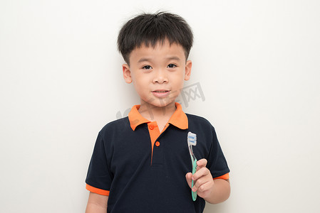 快乐的小男孩在白色背景上拿着牙刷，一个健康的混血男孩的工作室肖像与牙刷隔离。